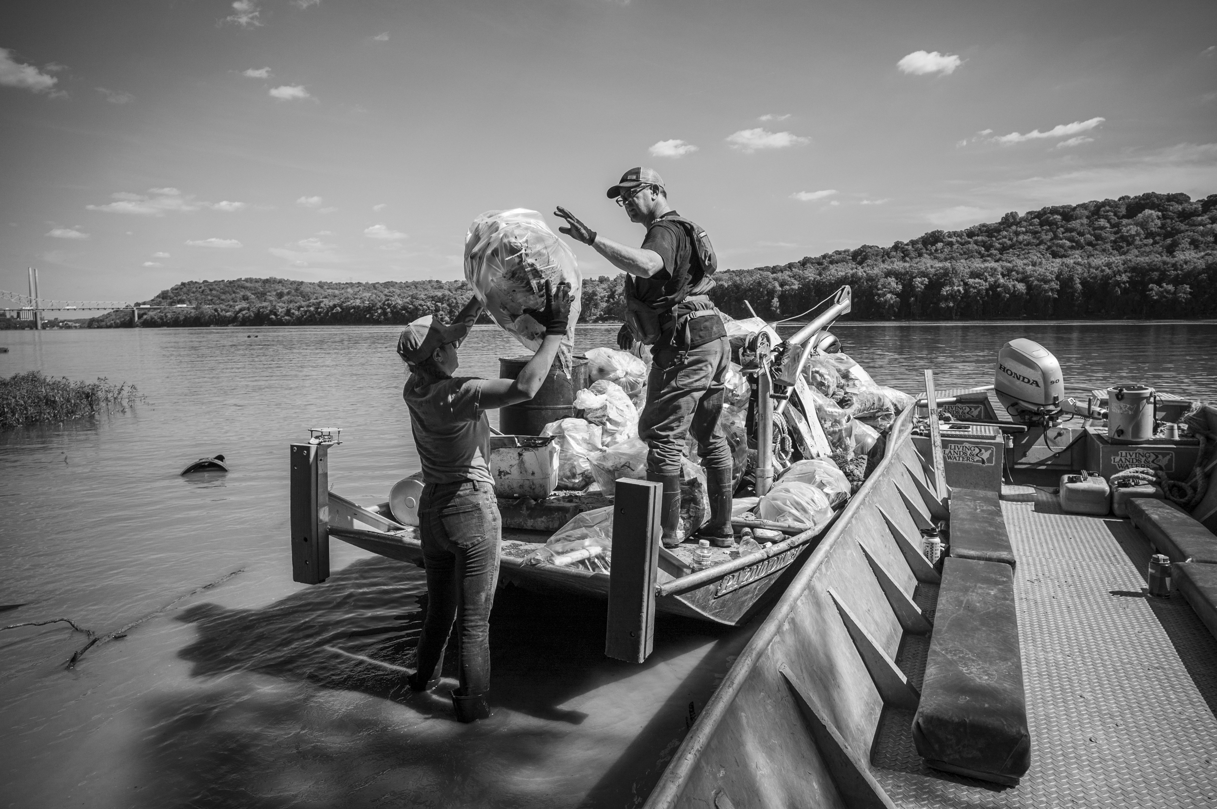 people loading bags of trash into a boat on the Ohio River